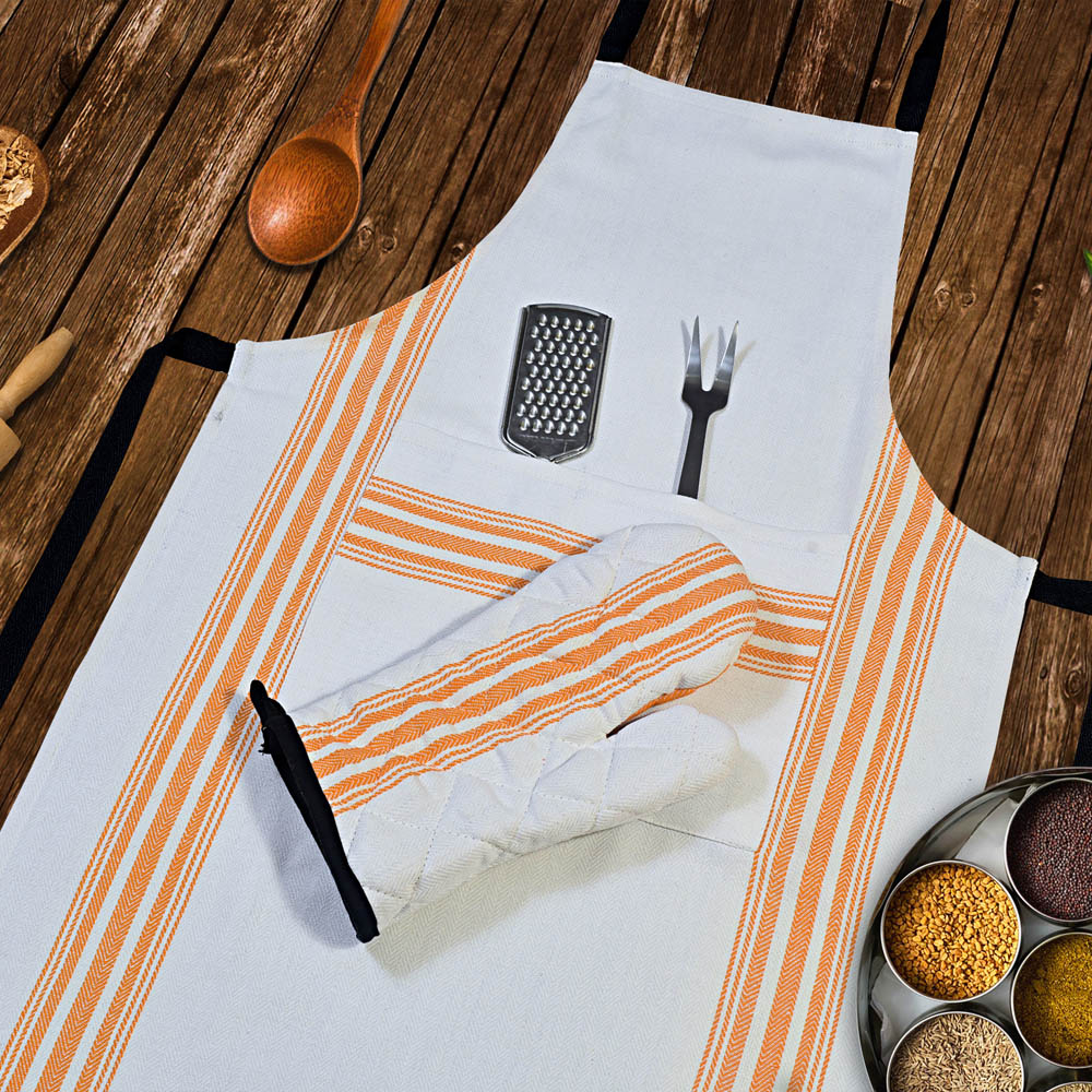 Apron with oven mitt and kitchen accessories on a wooden table