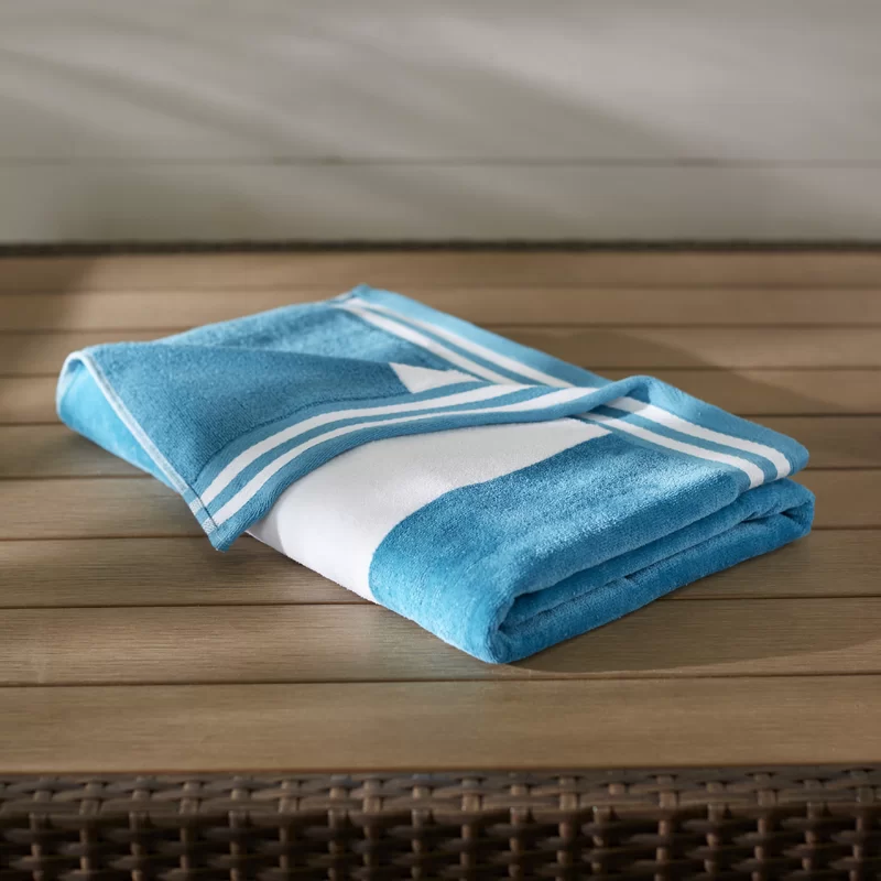Folded blue and white striped terry beach towel on a wooden deck